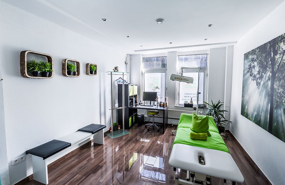 Moderner Behandlungsraum mit Therapieliege und großem Natur-Wandmotiv