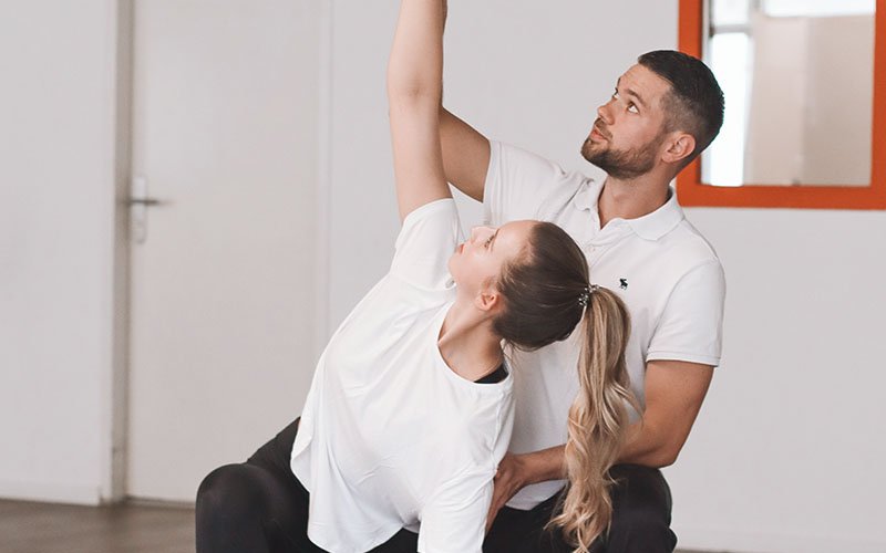 Physiotherapeut unterstützt Patientin bei einer Mobilisationsübung im Stehen